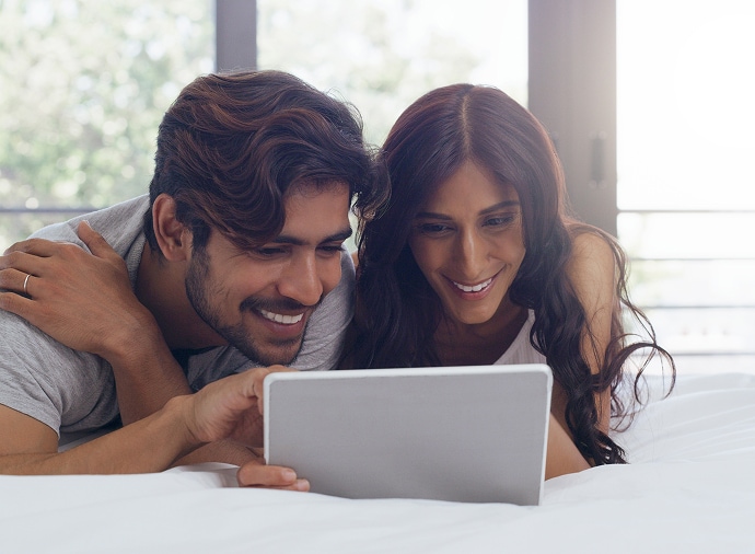 Άνδρας και γυναίκα γελάνε κοιτώντας ένα tablet
