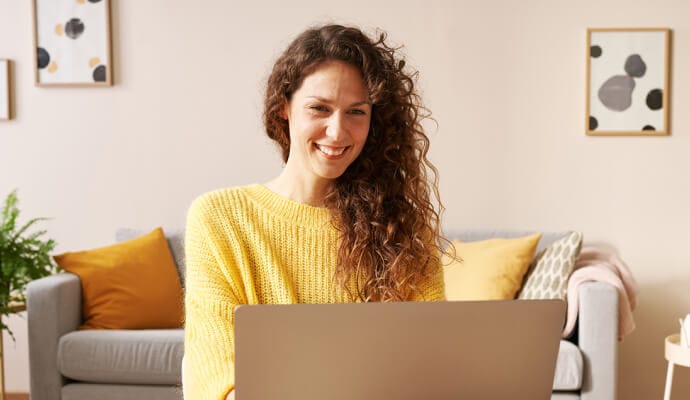 Γυναίκα που χαμογελά σε φορητό υπολογιστή με ανοιχτό το Norton Safe Search.
